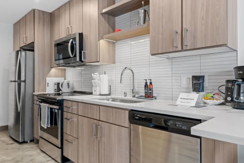 Modern kitchen featuring light wood cabinets, stainless steel appliances, and a white countertop.