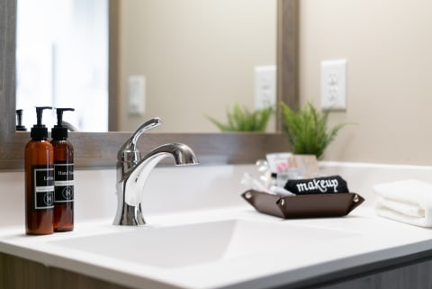 Modern bathroom countertop featuring lotion and soap, a shiny faucet, and decorative elements.
