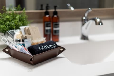 A neatly arranged bathroom countertop with a leather tray filled with toiletries and a towel labeled 'Makeup'.