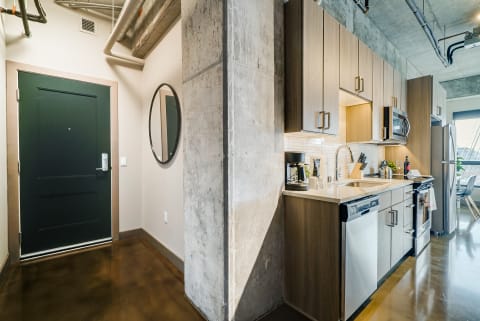 Modern kitchen area with dark green door and polished concrete floor.