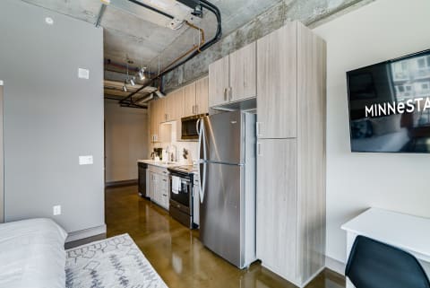 Interior of a modern studio apartment with a kitchen and workspace.