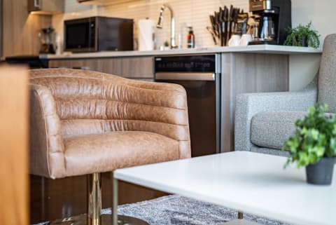 Cozy modern living room featuring a caramel-colored chair and a contemporary kitchen backdrop.