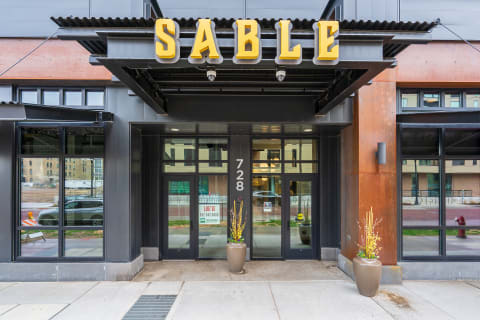 Modern building entrance with 'SABLE' signage and potted plant decoration.