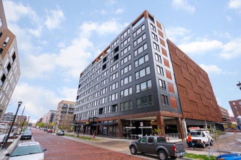 A contemporary multi-story building with large windows and a nearby brick-paved street.
