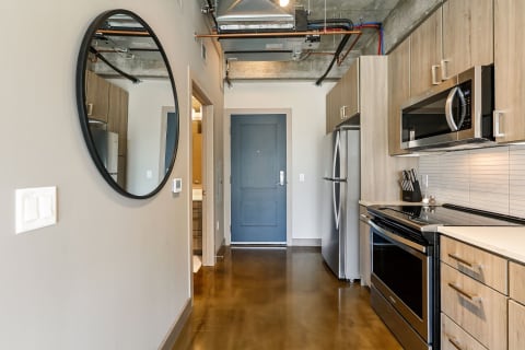 Modern kitchen design featuring wooden cabinets and stainless steel appliances with a polished concrete floor.