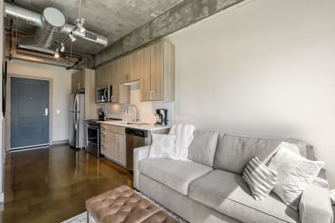 Stylish studio apartment with a gray sofa and a contemporary kitchen.