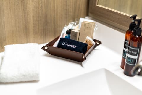 Bathroom counter with a brown tray containing cosmetics, a blue towel, and two bottles for lotion and hand soap.