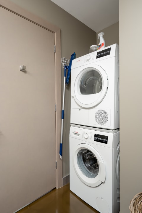 Compact laundry space with stacked appliances and cleaning supplies.