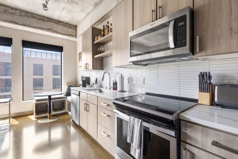 A contemporary kitchen featuring light wood cabinets, stainless steel appliances, and a cozy dining area by the window.