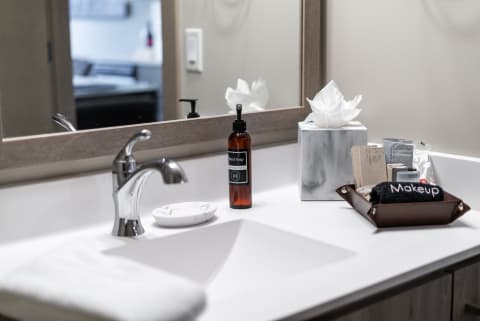 Contemporary bathroom countertop with hand soap, a towel, and skincare products.