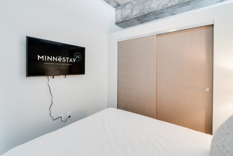 A sleek bedroom with a mounted TV displaying a vacation home logo and sliding closet doors.