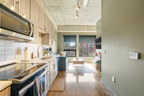 Modern kitchen and living room with a blue couch and city view.