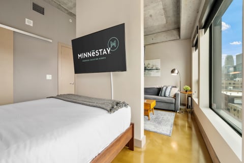 Modern apartment interior with a bed, television, and living area.