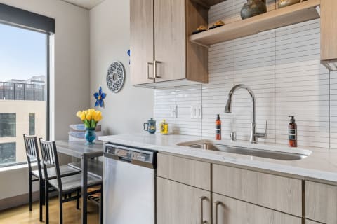 A contemporary kitchen with wooden cabinets, a sink, and a table adorned with yellow tulips.