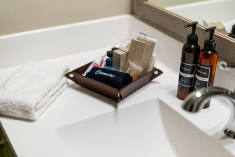 Bathroom counter with a brown leather tray containing toiletries and a folded white towel.