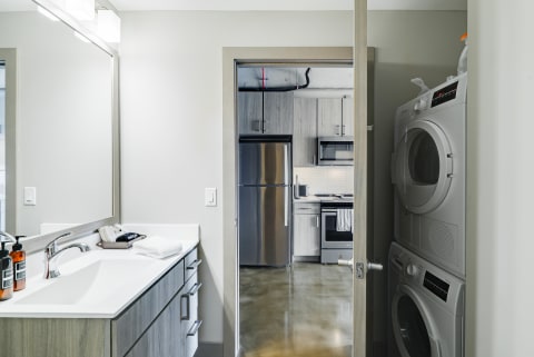 View of a contemporary bathroom and laundry area leading to an upscale kitchen.