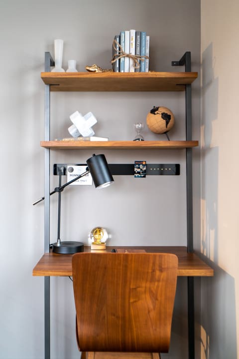 An elegant workspace with a wooden desk and shelves displaying books and decorative items.