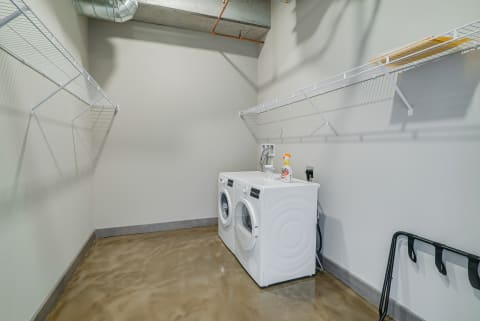 Modern laundry room with white washing machines and wire shelving.
