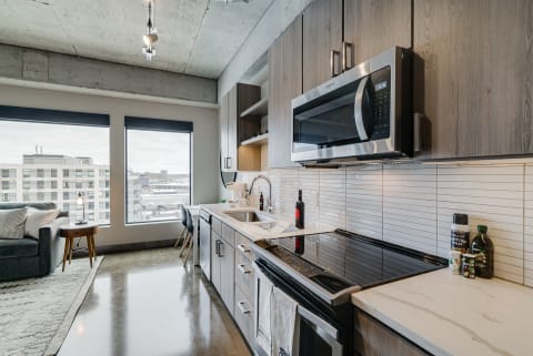 Modern kitchen with gray cabinets, stainless steel appliances, and urban views.