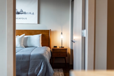 View of a modern bedroom with a bed, bedside table, and a decorative poster.