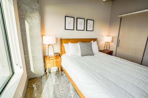 Modern bedroom with wooden bed frame, white bedding, and decorative pillows.