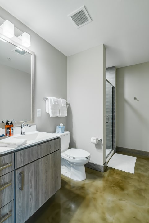 Modern bathroom interior featuring a sink, toilet, shower, and polished concrete floor.