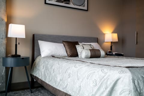 Cozy bedroom featuring a gray bed with decorative pillows and stylish lamps.
