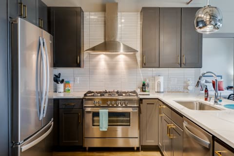 Modern kitchen featuring dark grey cabinets and a stainless steel gas stove.