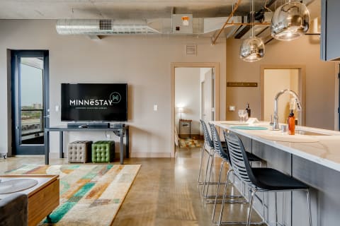 Interior view of a contemporary living room with a bar, TV, and balcony access.