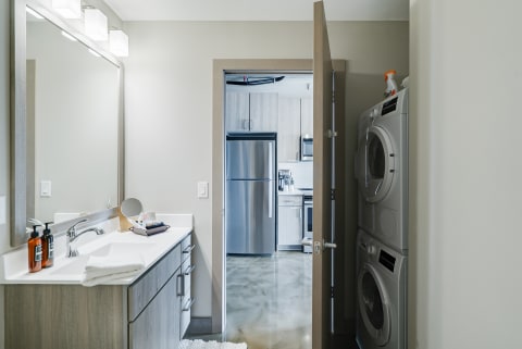 Modern bathroom with laundry appliances visible through the doorway.