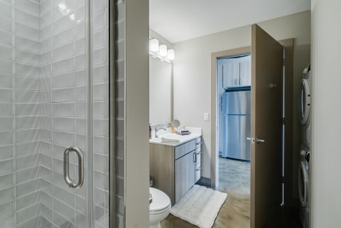 Modern bathroom interior with a walk-in shower and laundry area visible.