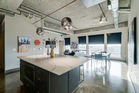 Contemporary open-concept living room and kitchen featuring a marble island and city view.