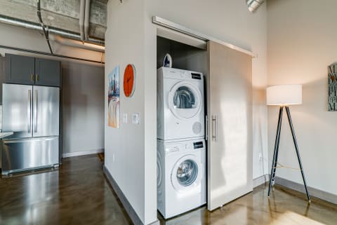 Compact laundry corner featuring a stacked washer and dryer, stainless steel refrigerator, and stylish decor.