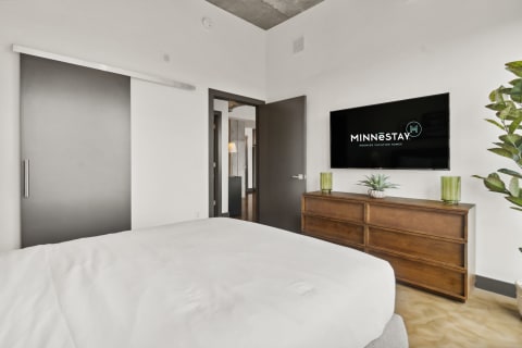 A modern bedroom featuring a sliding door, a flat-screen TV, and stylish decor.