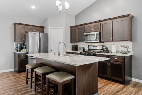 A contemporary kitchen with brown cabinets, granite countertop, and stainless steel appliances.