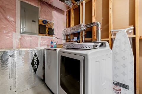 Laundry room with dryer, laundry basket, and ironing board in a basement setting.