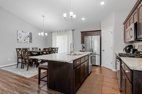 Stylish kitchen and dining space with dark wood furniture and stainless steel appliances.