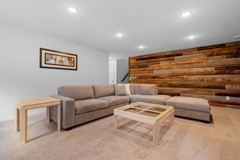 Cozy living room with a sectional sofa and wooden accent wall.