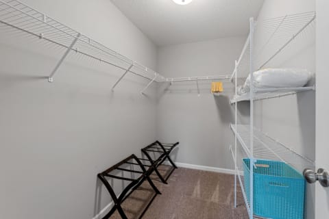 Interior view of a walk-in closet featuring wire shelving, wooden racks, and a teal basket.