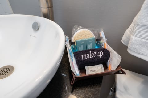 Bathroom countertop with a white sink and a wooden tray containing toiletries and a blue towel labeled 'makeup.'