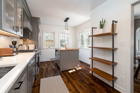 Bright and modern kitchen featuring gray cabinetry, hardwood floors, and a wood-topped island.