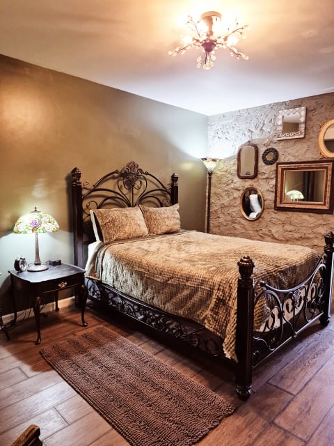 A charming bedroom with an ornate iron bed, vintage decor, and warm, inviting lighting.