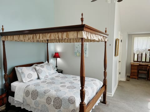 Elegant bedroom with a canopy bed and wooden desk, showcasing soft colors and intricate details.