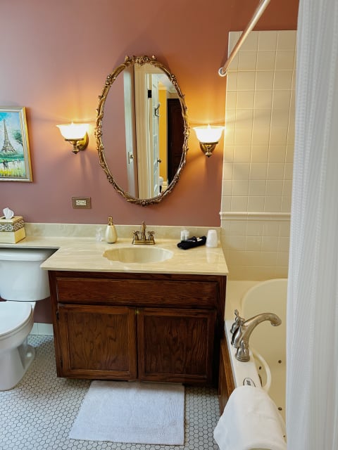 A vintage-style bathroom with a golden mirror, warm lighting, and elegant fixtures.