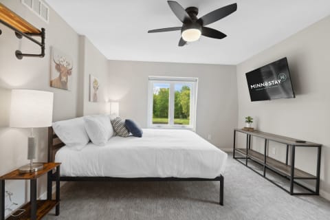 Stylish bedroom featuring a bed, modern lighting, and a view outside.