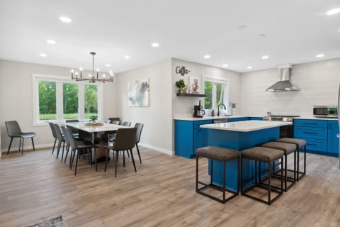 A contemporary kitchen and dining space featuring blue cabinets, a dining table, and large windows.