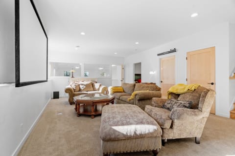 Cozy living room featuring patterned furniture, a glass coffee table, and a movie screen.