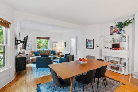 A beautifully designed open living and dining area featuring a wooden table, comfortable seating, and colorful decor.