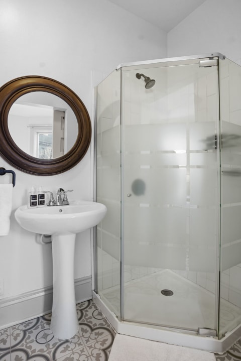 A modern bathroom showcasing a glass shower and a vintage-inspired sink.