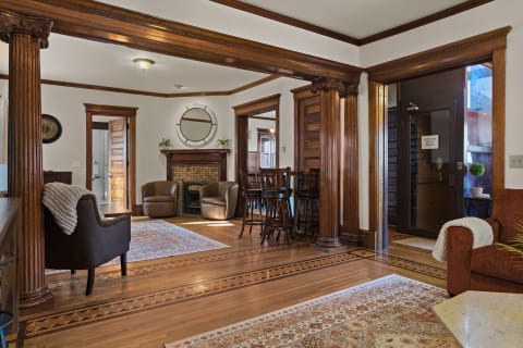 An elegant living room with brown leather chairs, hardwood floors, and a decorative fireplace.